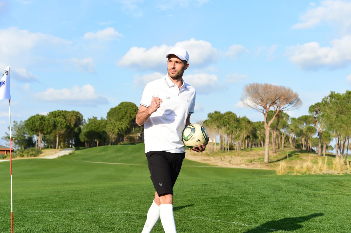 Jugador de footgolf con balón en mano junto a bandera de hoyo